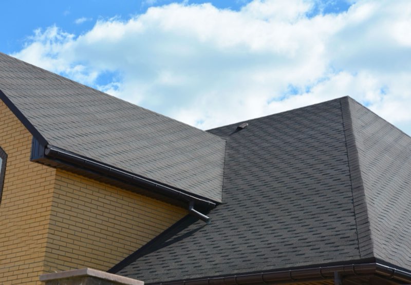 Shingled residential roof under a blue sky